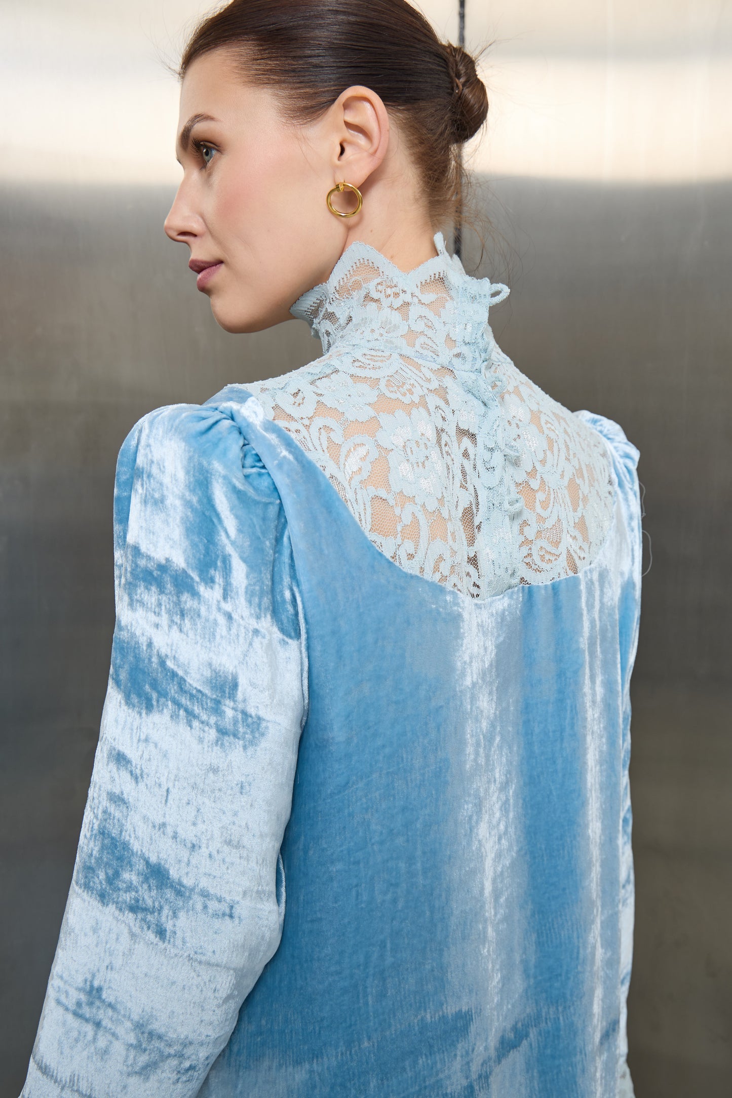 "Macro shot of the fine lace embroidery on the collar of the light blue velvet kaftan, emphasizing the premium finish and sustainable design quality."