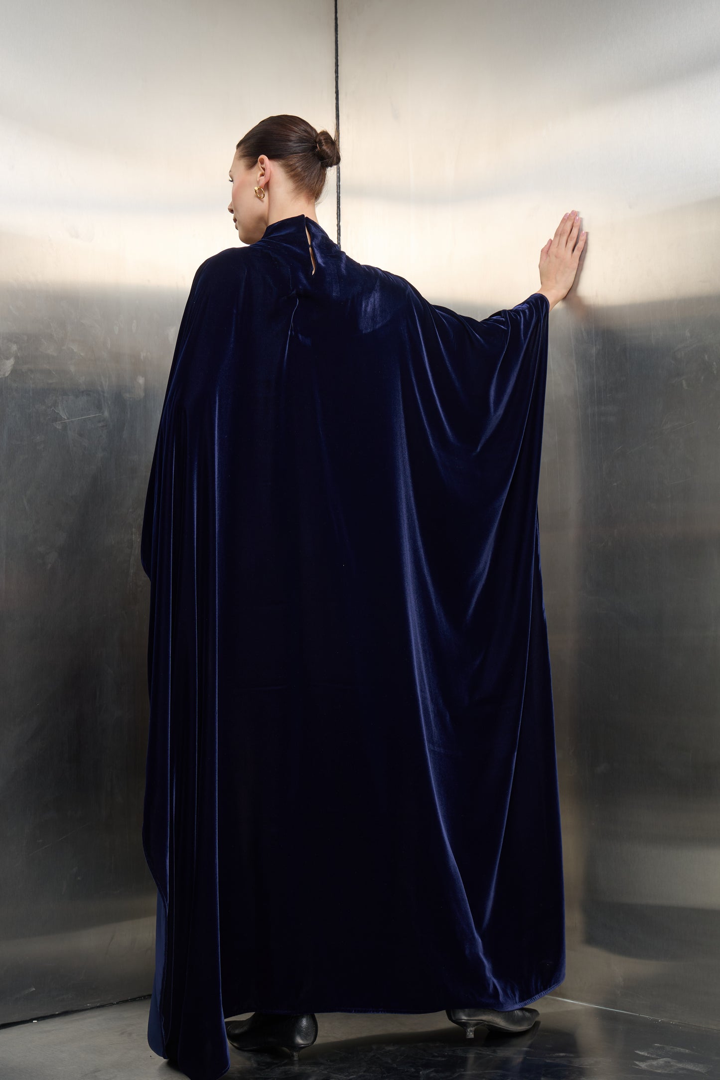 Rear view of the navy blue luxury cape kaftan, emphasizing the flowing crepe fabric and timeless velvet structure designed for the modern visionary woman.