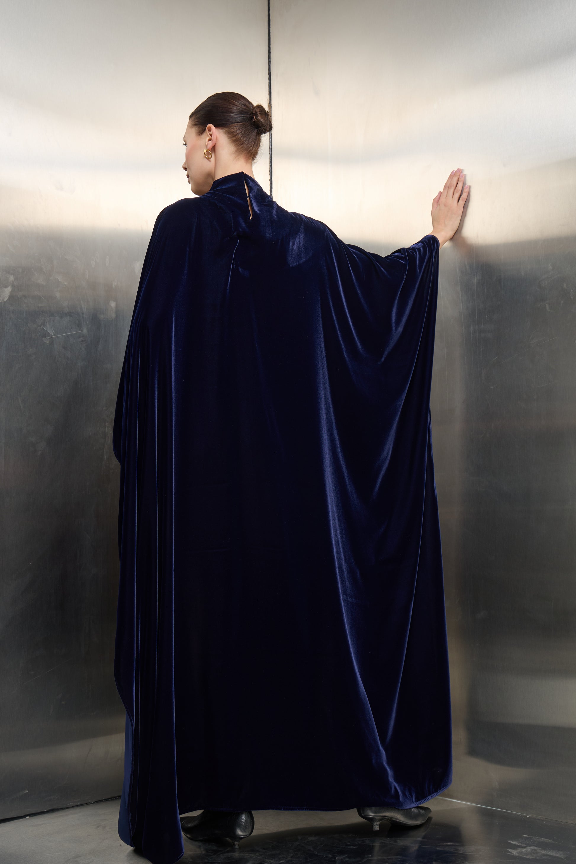 Rear view of the navy blue luxury cape kaftan, emphasizing the flowing crepe fabric and timeless velvet structure designed for the modern visionary woman.