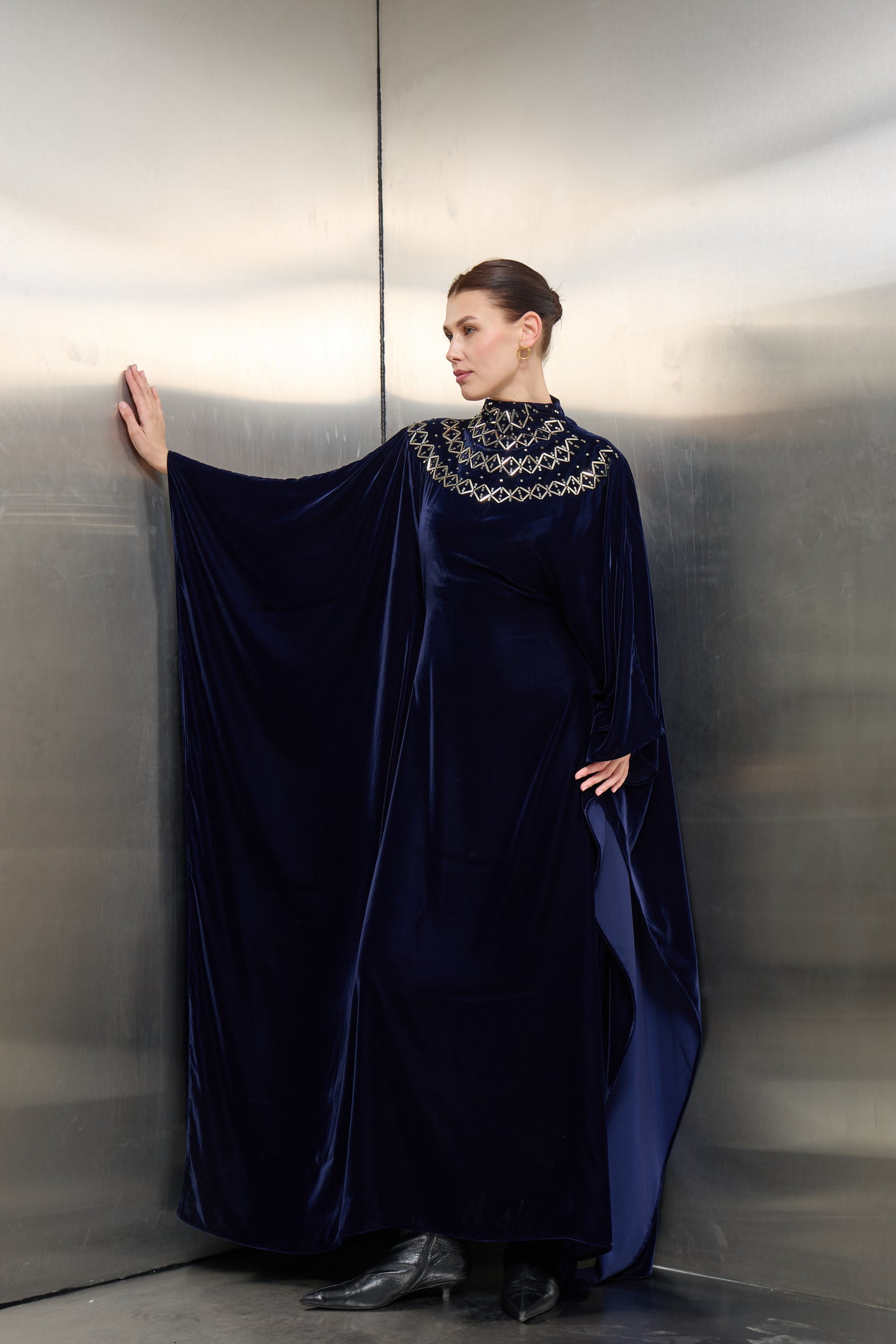 Mona Al Shebil Navy blue velvet cape kaftan with silver-stone neck embellishments, a high-end Saudi designer ready-to-wear piece for formal occasions.