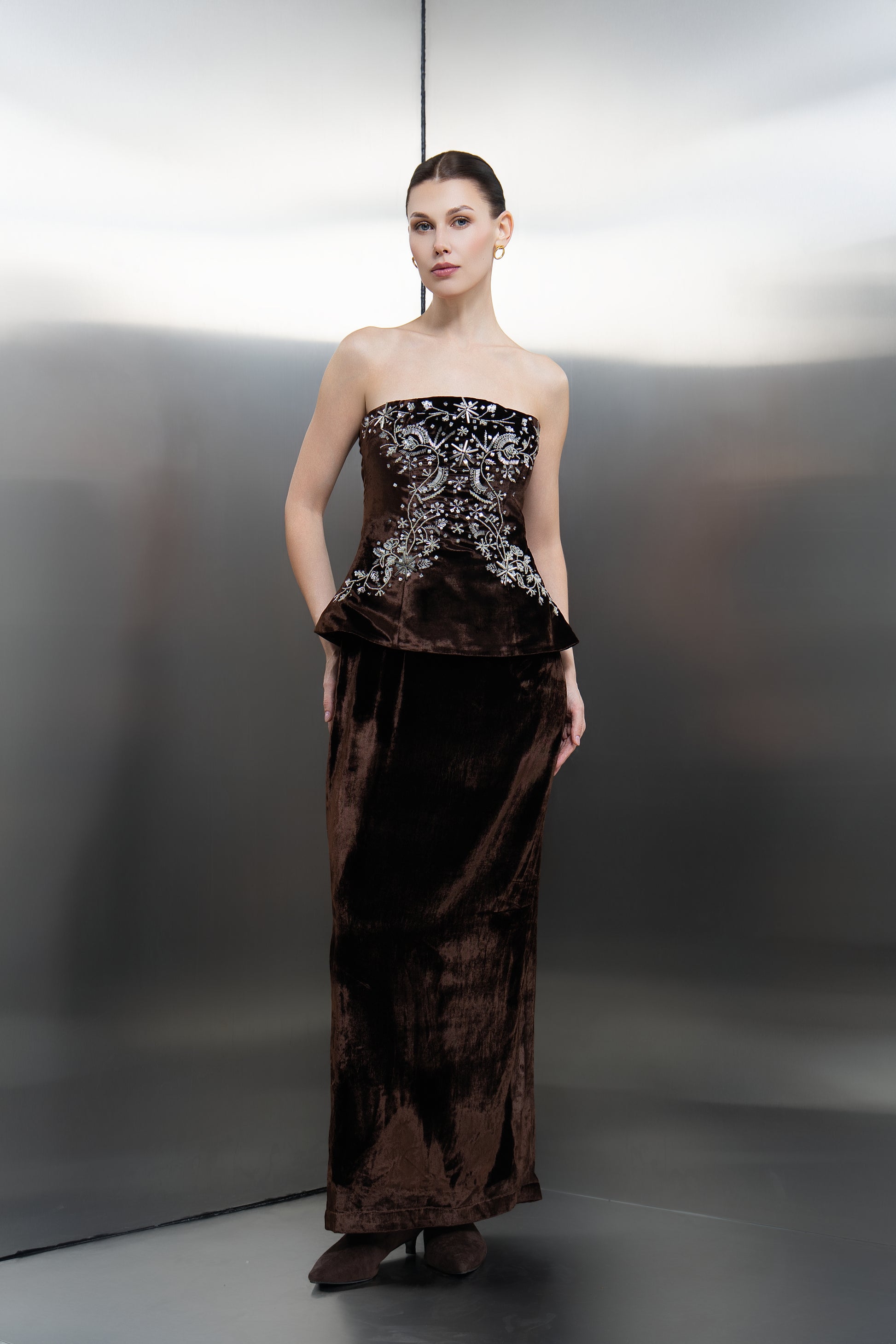 "Front view of the Mona Al Shebil brown velvet strapless corset with intricate silver floral embroidery, paired with a tailored floor-length velvet skirt."
