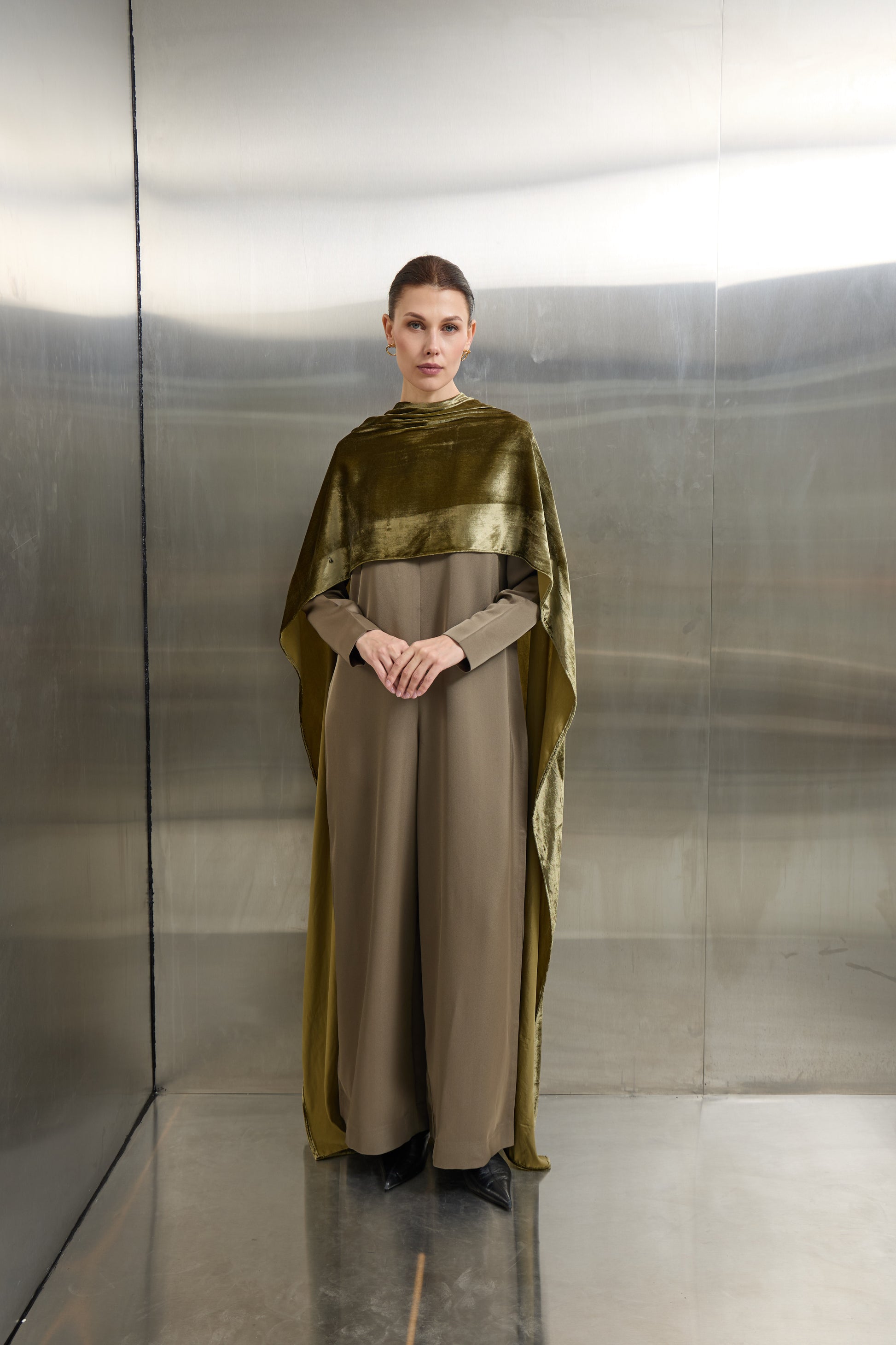 Mona Al Shebil Olive Green tailored jumpsuit paired with a matching velvet cape, offering a modern, empowered silhouette for Saudi luxury fashion."
