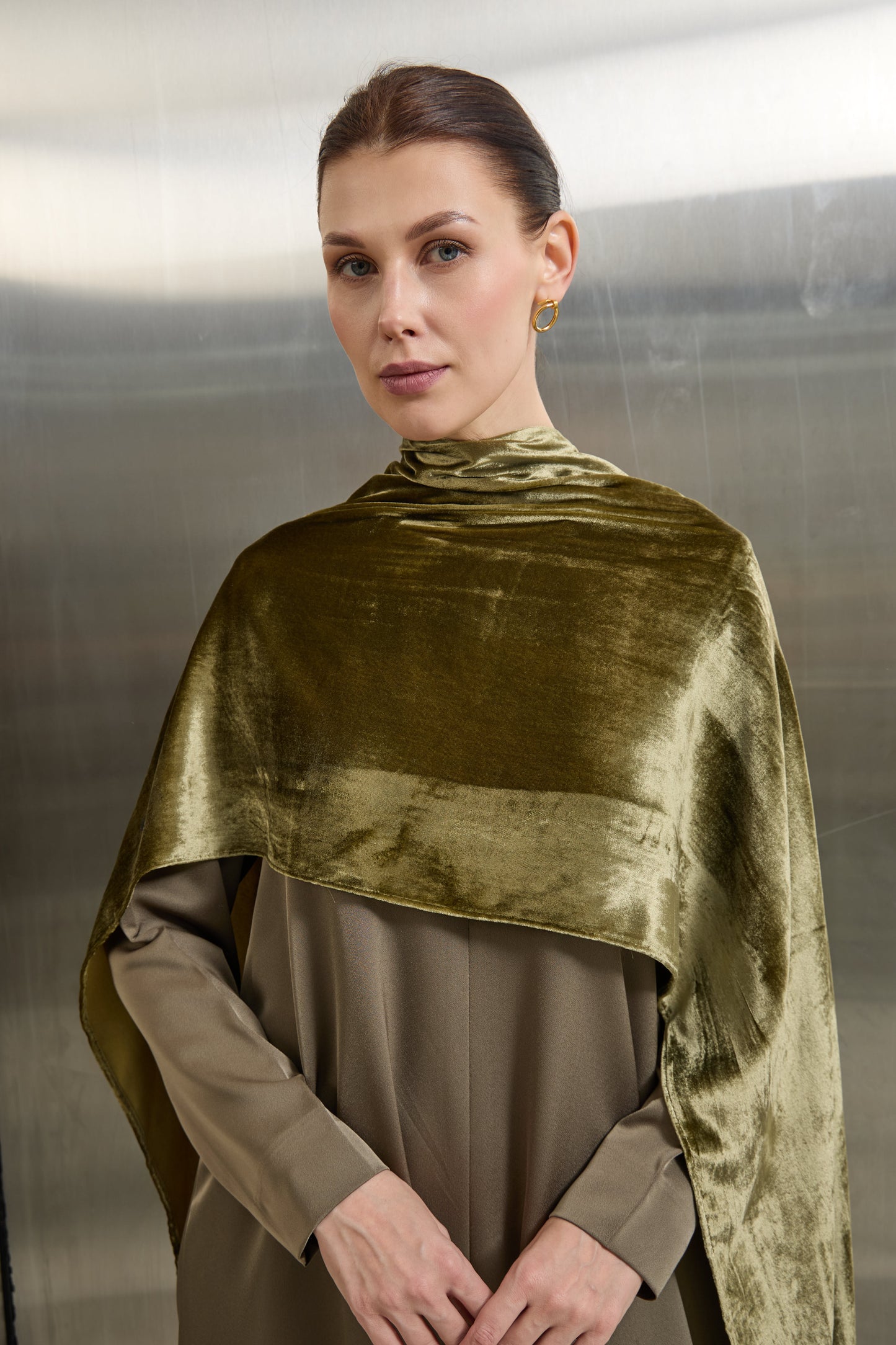 "Detailed contrast between the matte tailored fabric and the plush velvet cape on the Mona Al Shebil olive green jumpsuit, highlighting the high-end monochromatic craftsmanship."