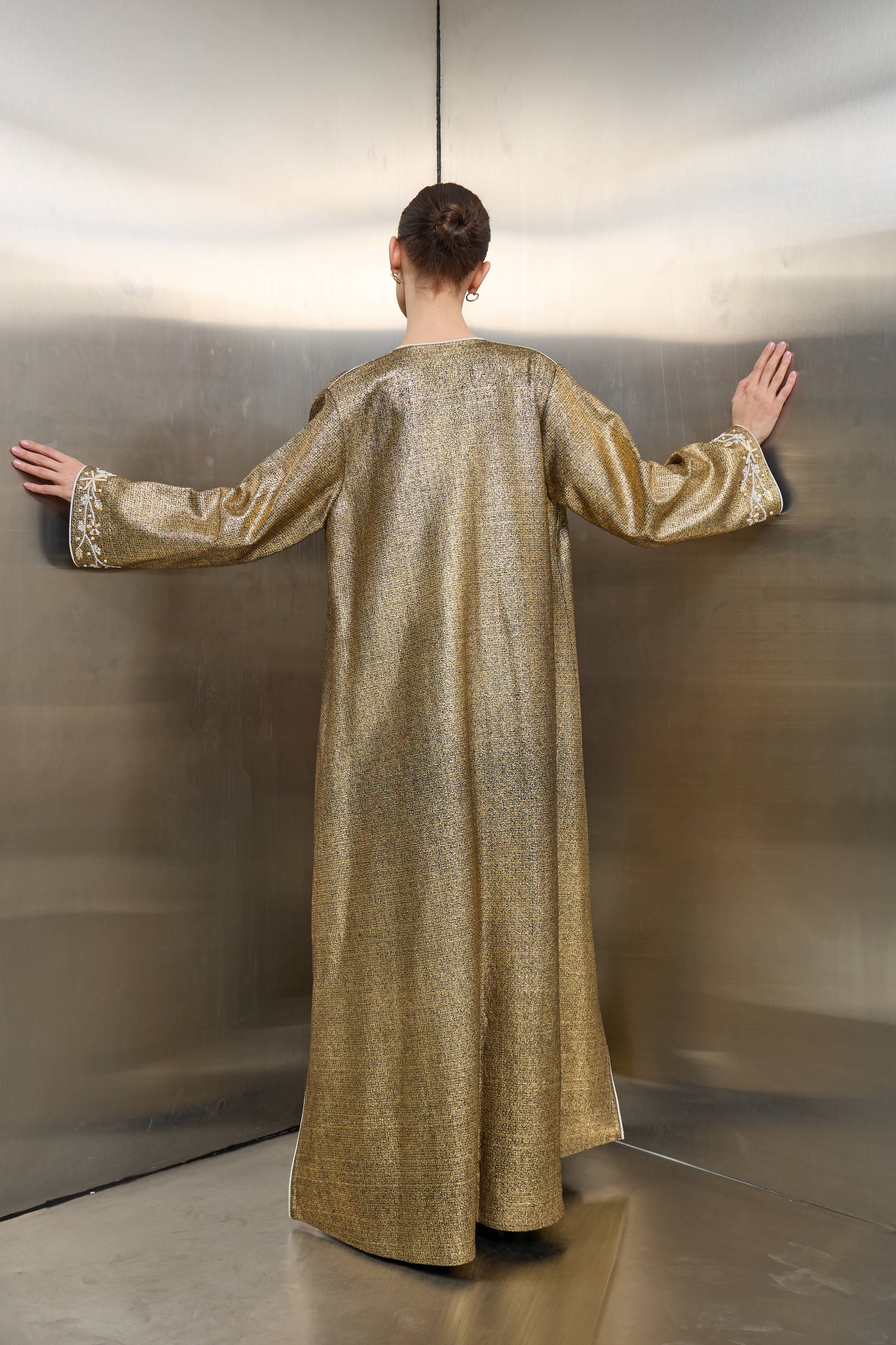 Back profile of the gold tweed kimono jacket by Mona Al Shebil, showcasing a tailored floor-length silhouette and professional elegance for high-end modest-wear."