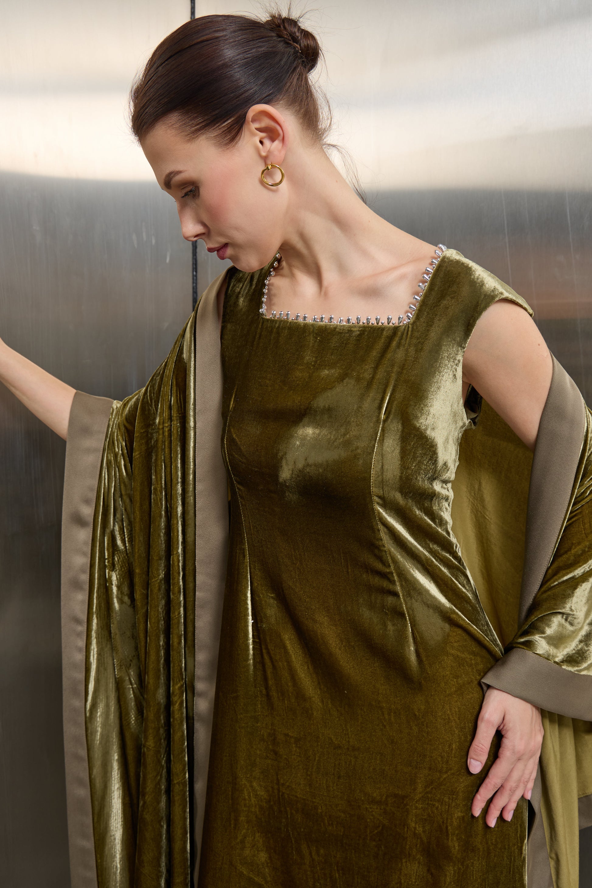 "Detailed view of the delicate silver sequin embellishment on the square neckline of the olive green velvet dress, showcasing premium Saudi craftsmanship."