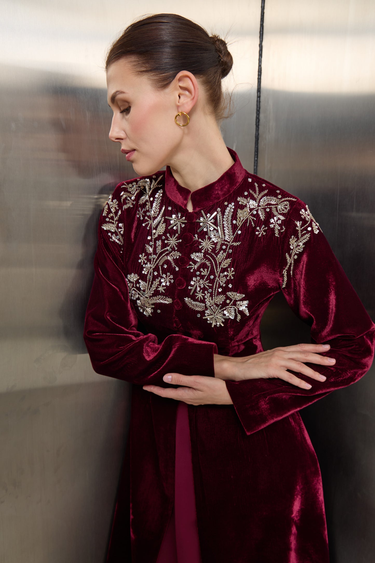Close-up of intricate silver thread embroidery and crystal detailing on the burgundy velvet collar of a Mona Al Shebil designer jacket, showcasing high craftsmanship.