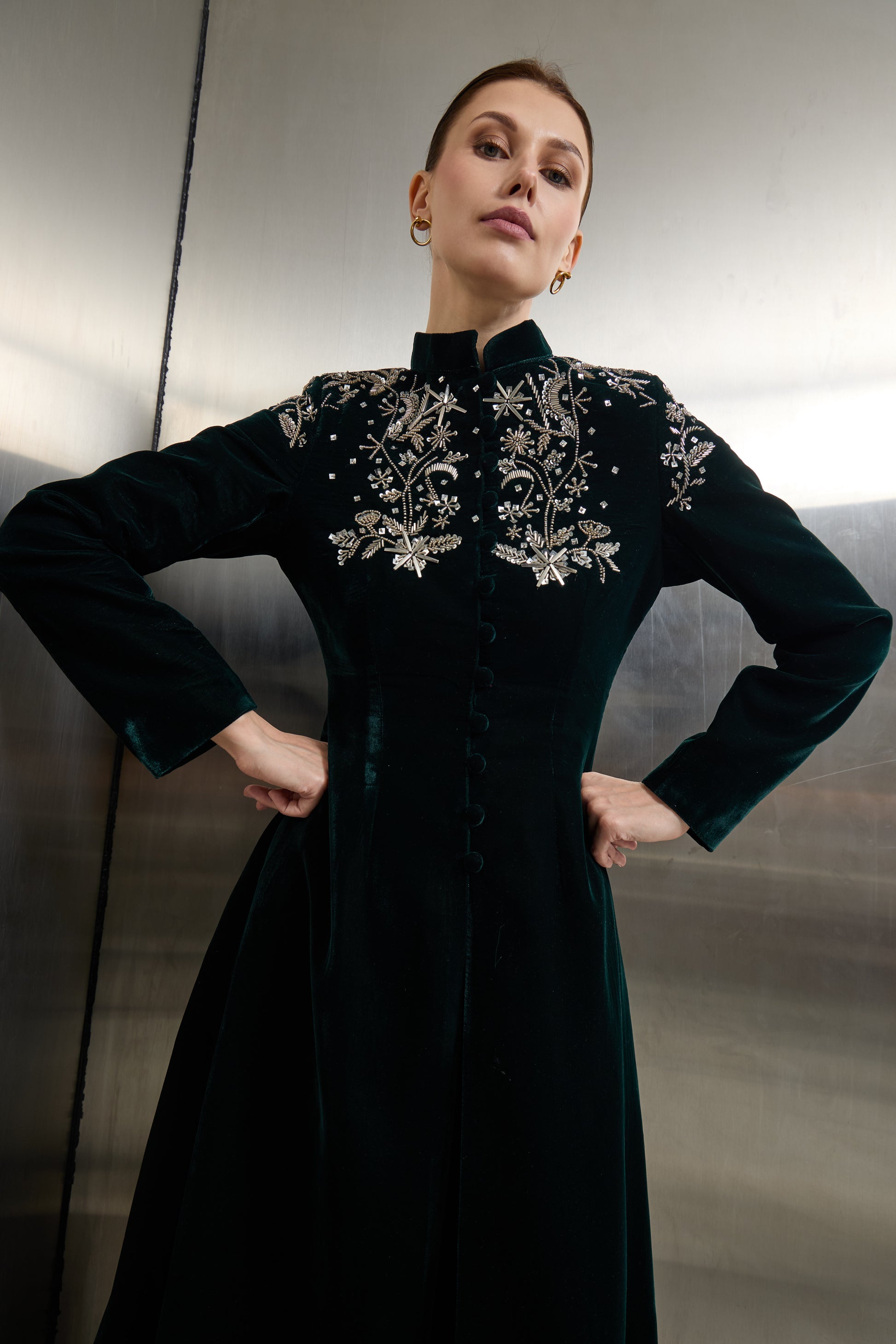 Detailed view of the metallic silver floral embroidery on a deep green velvet jacket by Mona Al Shebil, highlighting the signature craftsmanship of the Saudi brand.