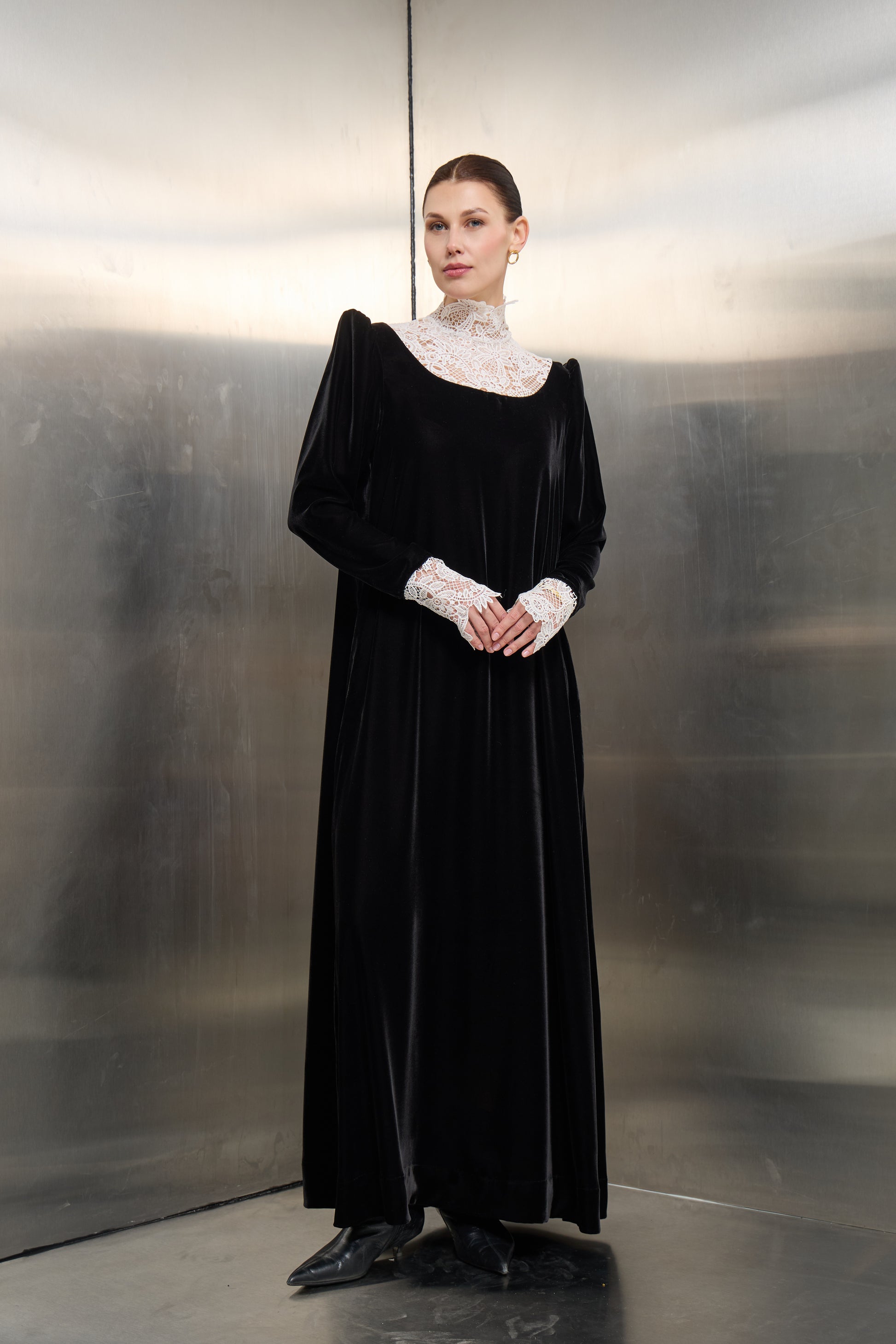 Mona Al Shebil Black velvet kaftan featuring a high-neck white lace collar and matching lace cuffs, offering a timeless luxury silhouette for formal modest occasions.