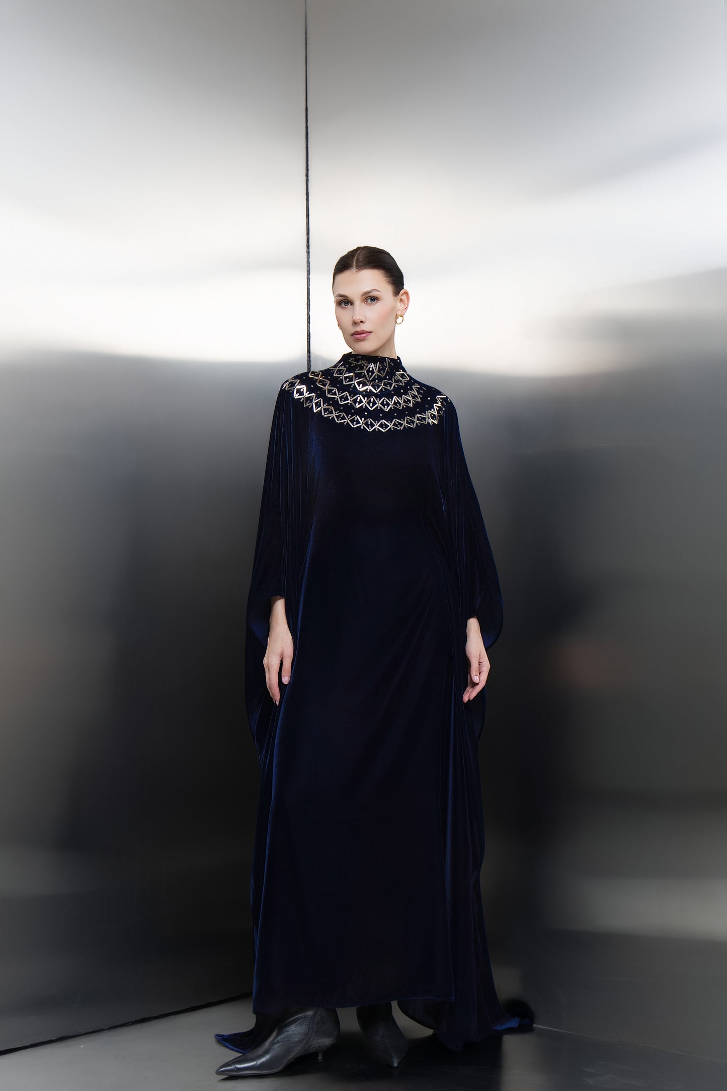 Mona Al Shebil Navy blue velvet cape kaftan with silver-stone neck embellishments, a high-end Saudi designer ready-to-wear piece for formal occasions.