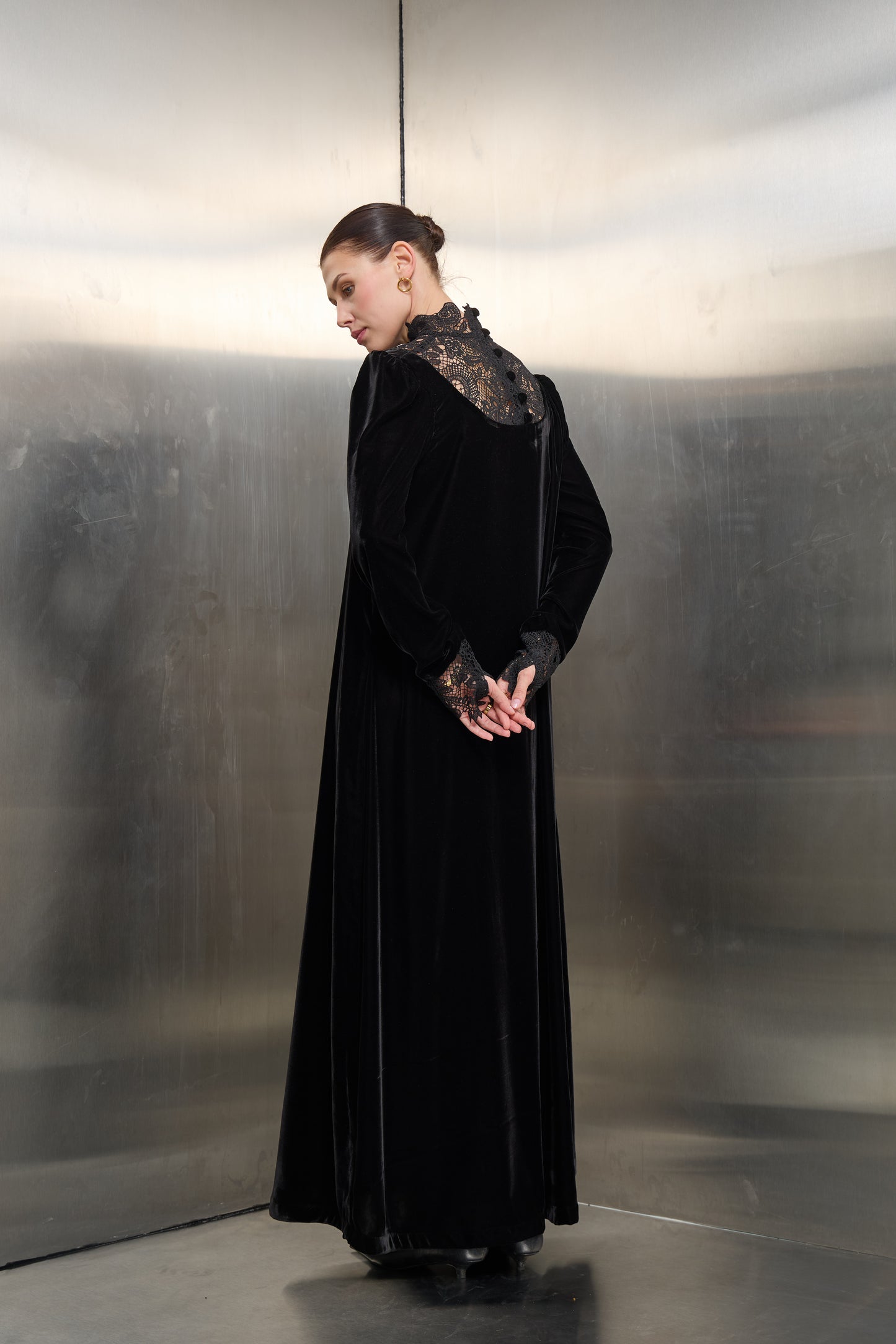 "Rear view detail of the black velvet kaftan by Mona Al Shebil, showcasing the intricate white lace back panel with elegant button closures."